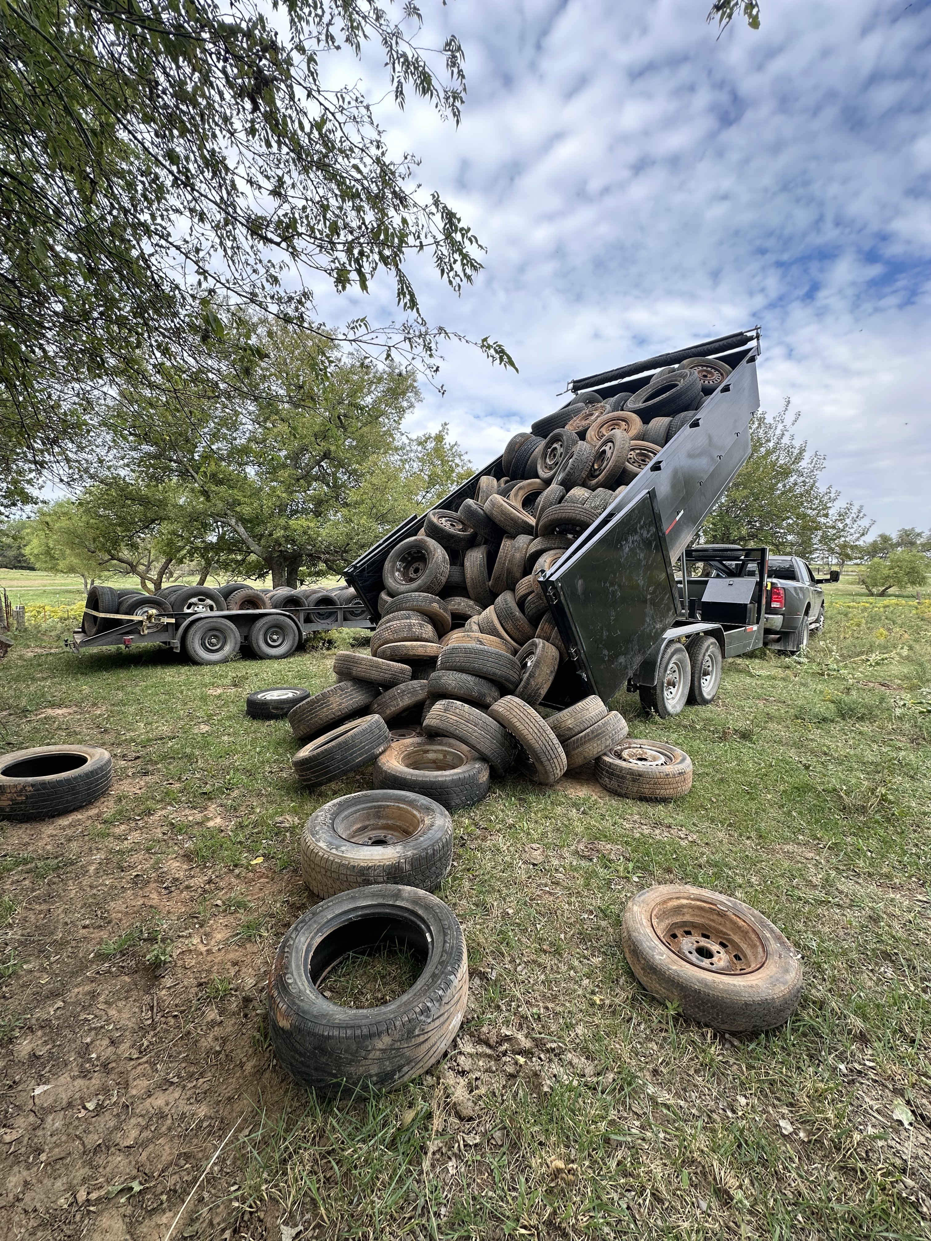 Big Trucking LLC dump trailer unloading tires during junk removal in Oklahoma City rural area